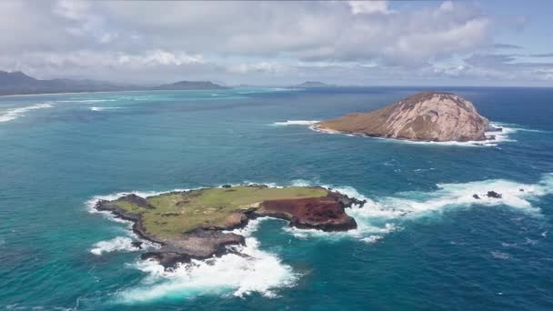 Létající dron nad oceánem. Pohled na Králičí ostrov. Vlny Tichého oceánu omývají žlutý písek tropické pláže. Nádherné hory havajského ostrova Oahu. — Stock video