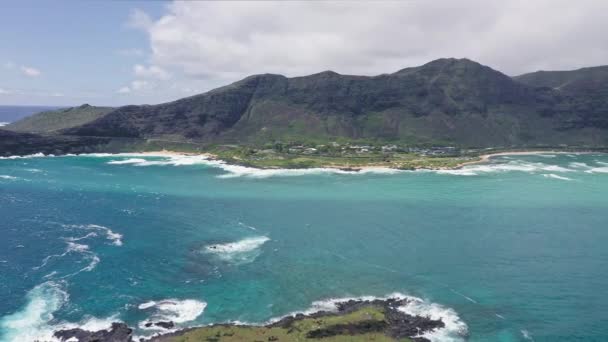 Létající dron nad oceánem. Pohled na Králičí ostrov. Vlny Tichého oceánu omývají žlutý písek tropické pláže. Nádherné hory havajského ostrova Oahu. — Stock video