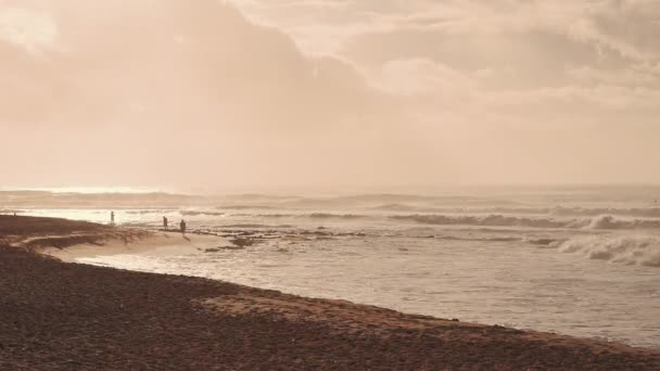海の上で劇的な日の出。ハワイのオアフ島の砂浜。人々はビーチに沿って歩く。太陽の光が雲を突破する。水に沿って日当たりの良いパス. — ストック動画