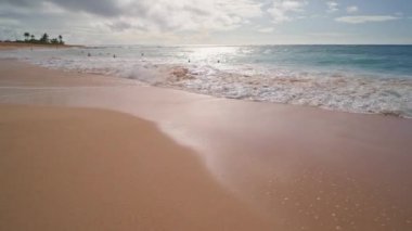 İnsanlar okyanusta yüzer. Oahu Hawaii 'nin tropikal adasındaki Sandy Plajı' nda sarı kum. Pasifik Okyanusu suyunun turkuaz rengi. Steadicam çekimi.