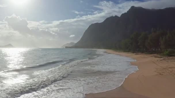 Vue aérienne colorée des montagnes rocheuses. Une plage tropicale avec de l'eau de mer bleu turquoise et des vagues qui claquent sur une plage de sable blanc cachée. Plage de Waimanalo, île d'Oahu, Hawaï. — Video