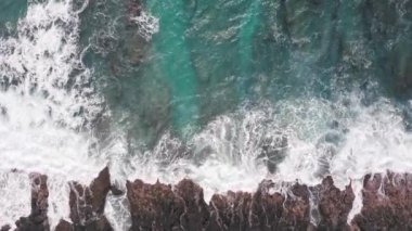 İHA 'dan hava görüntüsü. Kayalık okyanus kıyısının en üst manzarası. Pasifik Okyanusu 'nun Mavi Dalgaları kayaya çarpıyor. Beyaz deniz köpüğü. Tropik ada Oahu Hawaii 'nin volkanik plajı.