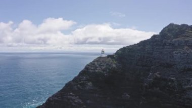 Okyanusun üzerinde uçan bir dron. Masapuu deniz feneri manzarası. Pasifik Okyanusu 'nun dalgaları Rocky sahilini yıkıyor. Hawaii 'nin muhteşem dağları Oahu adasına karşı beyaz bulutlu mavi gökyüzü..