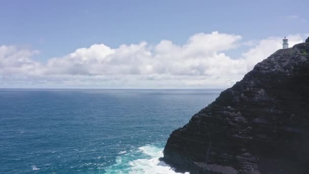 Repülő drón az óceán felett. Kilátás a Makapuu világítótoronyra. Csendes-óceáni hullámok mossák a sziklás partokat. Csodálatos hegyei Hawaii sziget Oahu háttér kék ég fehér felhők. — Stock videók