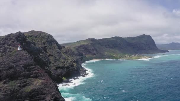 Repülő drón az óceán felett. Kilátás a Makapuu világítótoronyra. Csendes-óceáni hullámok mossák a sziklás partokat. Csodálatos hegyei Hawaii sziget Oahu háttér kék ég fehér felhők. — Stock videók