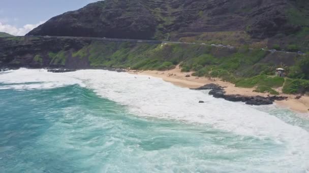 A Makapuu Beach Park felett repül. Óriási hullámok habzanak és fröcskölnek az óceánban. A Csendes-óceán vizének türkiz színe a trópusi szigeten. Csodálatos hegyei Hawaii szigetének, Oahunak.. — Stock videók