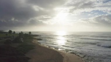 Oahu Hawaii Adası 'nda hava görüntüsü. Drone kumlu bir sahilde uçuyor. Kayalık dağların manzarası. Tropikal bir adada sabahın erken saatlerinde. Pasifik Okyanusu 'nun dalgaları kıyıları siler..