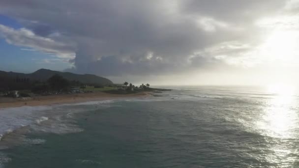 Légi felvétel Oahu Hawaii szigetén. Drón repül a homokos parton. Kilátás a sziklás hegyekre. Kora reggel egy trópusi szigeten. A Csendes-óceán hullámai mossák a partot. — Stock videók