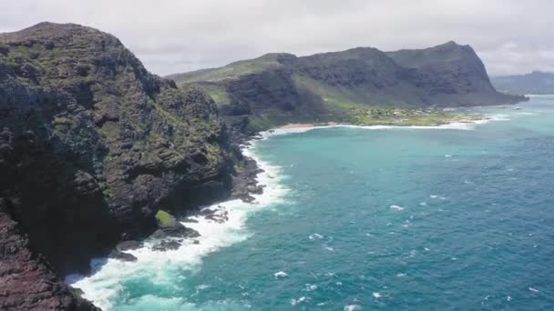 Repülő drón az óceán felett. Madártávlatból lőni. Csendes-óceáni hullámok mossák a sziklás partokat. Csodálatos hegyei Hawaii sziget Oahu háttér kék ég fehér felhők. — Stock videók