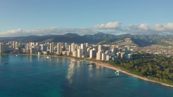 Panning antenowy dron powoli latający nad kolorowym Honolulu Skyline podczas Sunset w Oahu, Hawaje z Waikiki Beach Strzelanie z lotu ptaka. Wspaniałe góry hawajskiej wyspy Oahu. — Wideo stockowe