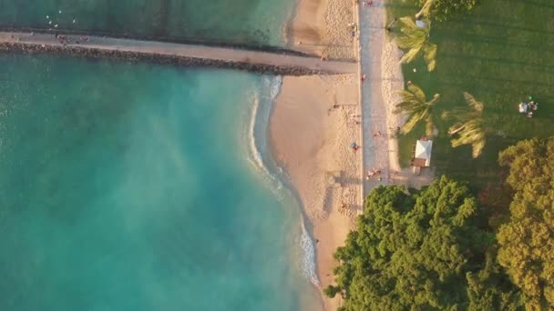 Flug aus der Luft über einen tropischen Strand. Videodreh im Kino. Drohne fliegt während des Sonnenuntergangs langsam über die bunte Landschaft auf der Insel Oahu, Hawaii, mit dem Strand von Waikiki. — Stockvideo