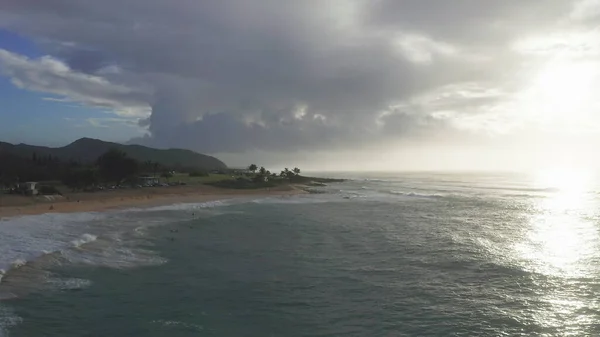 Luftaufnahme auf der Insel Oahu Hawaii. Drohne fliegt über einen Sandstrand. Blick auf die felsigen Berge. Früh morgens auf einer tropischen Insel. Wellen des Pazifischen Ozeans spülen die Küste. — Stockfoto