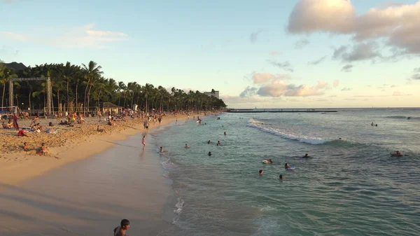 Honolulu, Hawaii - 15 marzo 2021: Splendido tramonto sulla spiaggia di Honolulus Waikiki. I surfisti cavalcano le onde. Turisti prendere il sole sulla spiaggia. — Foto Stock