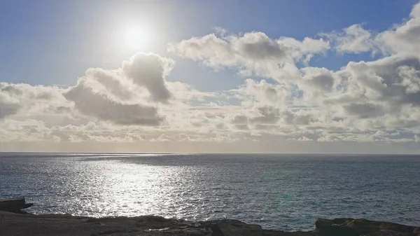 Sunrise over the island of Oahu. White clouds float across the blue sky. Blue Waves of the Pacific Ocean Beats Oahu Island Volcanic Cliffs. Turquoise water color. Clear sunny day. DCI 4k — Zdjęcie stockowe