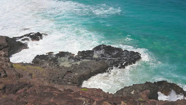 Голубые волны Тихого океана бьют по вулканическим скалам острова Оаху. Бирюзовый акварель. Светлый солнечный день. Архипелаг Гавайи. DCI 4k — стоковое фото