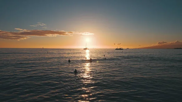 Úžasné barvy tropického západu slunce. Na obzoru oceánu se vznášely siluety plachetnic. Surfaři jezdí na vlnách. Oahu, letní dovolená na Havaji. — Stock fotografie