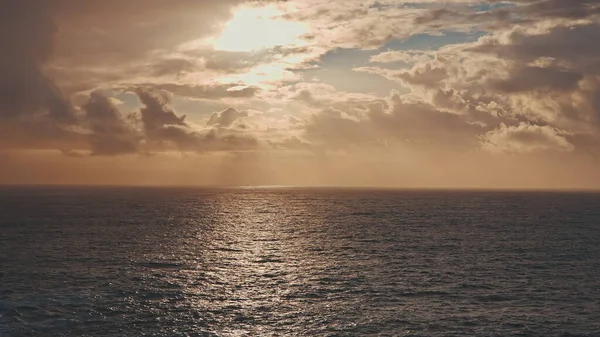 Dramatischer Sonnenaufgang über dem Ozean. Ein Sonnenstrahl bricht durch die Wolken. Sonniger Weg auf dem Wasser. — Stockfoto