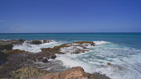 Blick auf die vulkanischen Klippen am tropischen Strand von Oahu Hawaii. Wellen krachen gegen die scharfen Kanten der Steine. Filmreifes 4K-Zeitlupenspiel. Unberührte Natur an einem sonnigen Sommertag. DCI. — Stockfoto