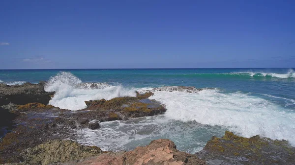 Blick auf die vulkanischen Klippen am tropischen Strand von Oahu Hawaii. Wellen krachen gegen die scharfen Kanten der Steine. Filmreifes 4K-Zeitlupenspiel. Unberührte Natur an einem sonnigen Sommertag. DCI. — Stockfoto