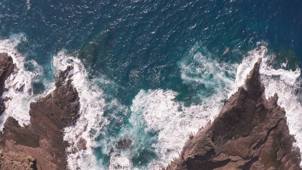 Letecký výstřel z dronu. Horní pohled na skalnaté pobřeží oceánu. Modré vlny Tichého oceánu padají na skálu. Bílá mořská pěna. Sopečná pláž tropického ostrova Oahu Havaj. — Stock fotografie