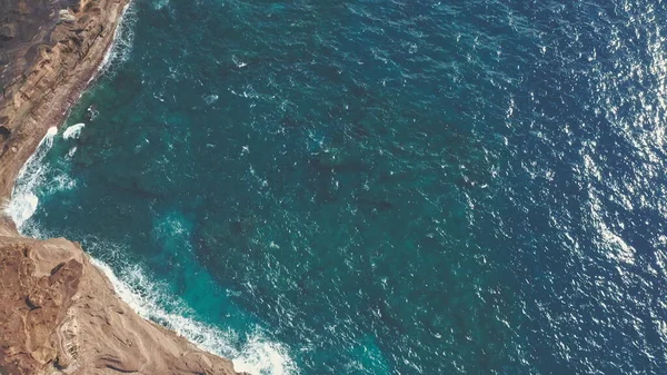 Letecký výstřel z dronu. Horní pohled na skalnatý oceánský břeh... modré vlny Tichého oceánu se hroutí na skálu. Bílá mořská pěna. Sopečná pláž tropického ostrova Oahu Havaj. — Stock fotografie