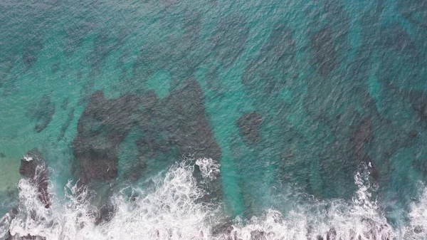 Letecký výstřel z dronu. Horní pohled na skalnaté pobřeží oceánu. Modré vlny Tichého oceánu padají na skálu. Bílá mořská pěna. Sopečná pláž tropického ostrova Oahu Havaj. — Stock fotografie