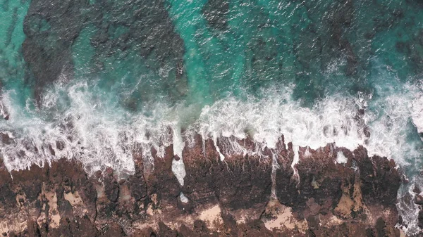 Повітряний постріл з дрона. Верхній вид на скелястий берег океану. Блакитні хвилі Тихого океану вдаряються об скелі. Біла морська піна. Вулканічний пляж на острові Оаху. — стокове фото
