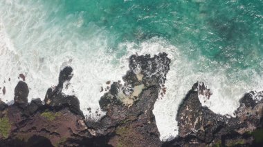İHA 'dan hava görüntüsü. Kayalık okyanus kıyısının en üst manzarası. Pasifik Okyanusu 'nun Mavi Dalgaları kayaya çarpıyor. Beyaz deniz köpüğü. Tropik ada Oahu Hawaii 'nin volkanik plajı.