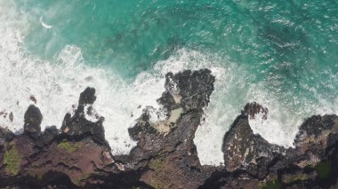 İHA 'dan hava görüntüsü. Kayalık okyanus kıyısının en üst manzarası. Pasifik Okyanusu 'nun Mavi Dalgaları kayaya çarpıyor. Beyaz deniz köpüğü. Tropik ada Oahu Hawaii 'nin volkanik plajı.