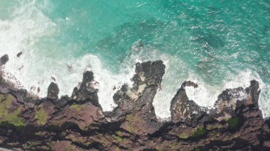 İHA 'dan hava görüntüsü. Kayalık okyanus kıyısının en üst manzarası. Pasifik Okyanusu 'nun Mavi Dalgaları kayaya çarpıyor. Beyaz deniz köpüğü. Tropik ada Oahu Hawaii 'nin volkanik plajı.