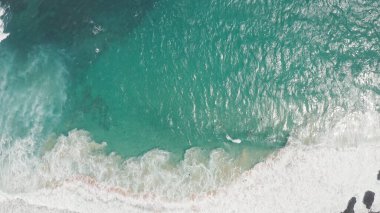 Altın saatinde okyanusun üzerinde uçmak. Okyanusta köpüren ve sıçrayan dev dalgalar. Sörfçüler dalgalara biner. Oahu Hawaii tropikal adasındaki Pasifik Okyanusu suyunun turkuaz rengi..