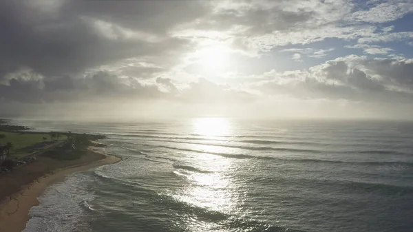 Luftaufnahme auf der Insel Oahu Hawaii. Drohne fliegt über einen Sandstrand. Blick auf die felsigen Berge. Früh morgens auf einer tropischen Insel. Wellen des Pazifischen Ozeans spülen die Küste. — Stockfoto
