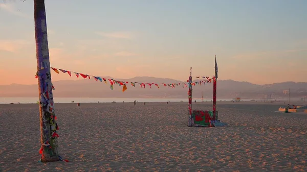 LOS ANGELES, CALIFORNIA, USA - 2020. december 10.: Venice Ocean Beach Skatepark. Kis zászlók lengenek a széltől egy kötélen, nyári naplemente háttér. Lassú mozgás.. — Stock Fotó