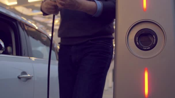 Homme utilisant le smartphone tout en rechargeant sa voiture électrique — Video