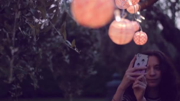 Молодая женщина делает селфи под фонарями — стоковое видео