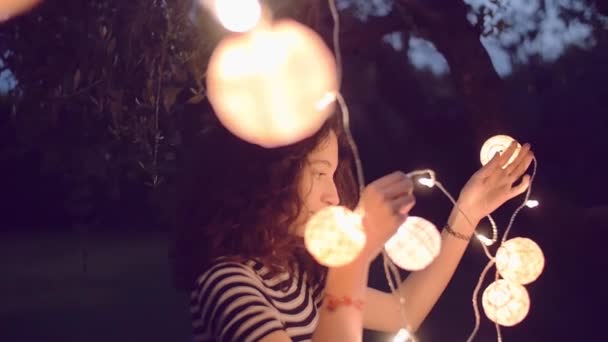 Замедленная съемка молодой женщины, украшающей ёлку фонариком — стоковое видео