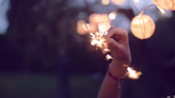 Plan au ralenti de la jeune femme allumant des étincelles dans le jardin — Video