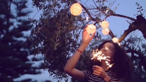 Tiro em câmera lenta de mulher jovem que ilumina sparklers no jardim — Vídeo de Stock