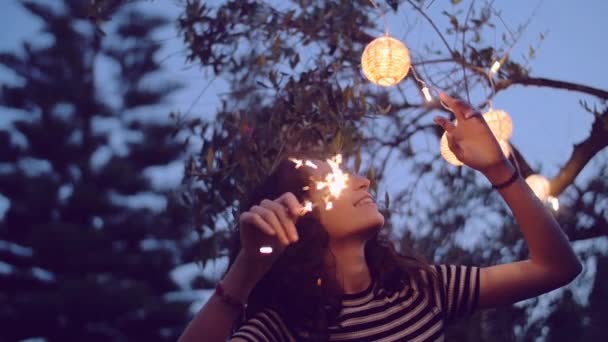 Tiro em câmera lenta de mulher jovem que ilumina sparklers no jardim — Vídeo de Stock
