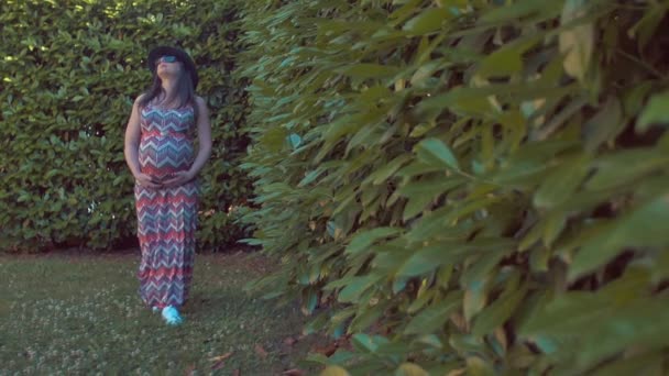 Zwangere vrouw wandelen in de tuin. shot in slow motion — Stockvideo