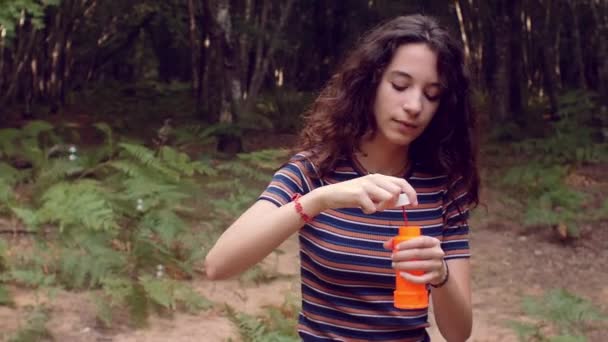 Slow-motion shot van meisje met plezier met zeepbellen in het bos — Stockvideo