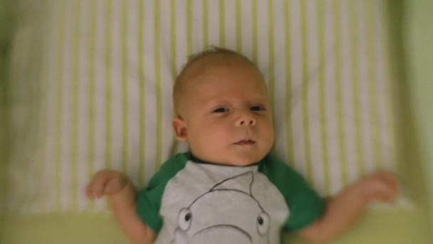 Menino recém-nascido olhar para carrossel brinquedo girar sobre a cama — Vídeo de Stock