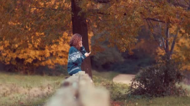 Meisje, zittend op het hek met behulp van smartphone — Stockvideo