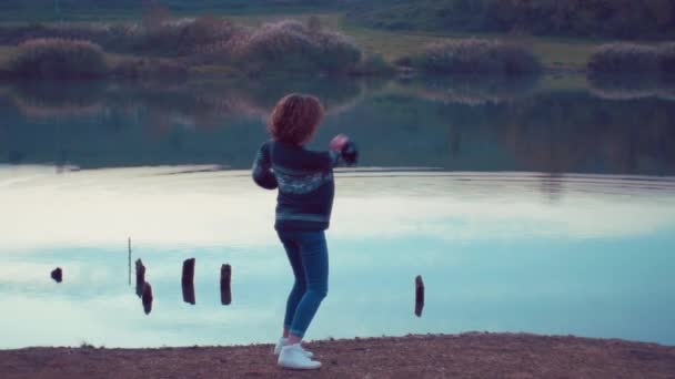 Chica lanzando piedras en el lago. Disparo en cámara lenta — Vídeos de Stock