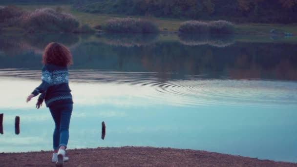 Chica lanzando piedras en el lago. Disparo en cámara lenta — Vídeo de stock