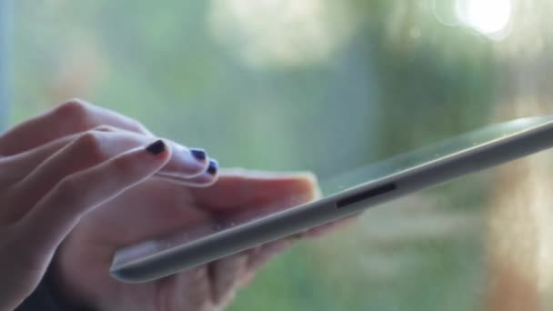 Kız bir dijital tablet kullanarak bir pencerenin yakınındaki — Stok video