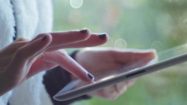 Kız bir dijital tablet kullanarak bir pencerenin yakınındaki