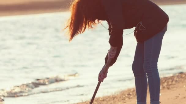 Flicka på stranden på sand med en pinne. — Stockvideo