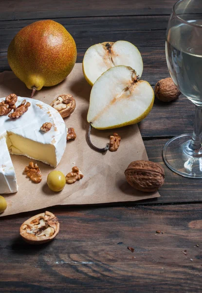 Сир камамбер з волоськими горіхами, медом і грушами на сільському столі. Склянка білого вина — стокове фото