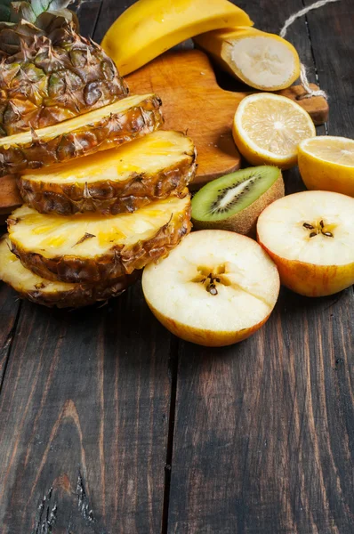 Färsk skivad ananas och frukter på ett bord av trä — Stockfoto